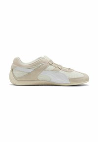 Zapatilla deportiva beige y blanca con material de ante y malla, diseño de perfil bajo, suela curvada y cierre de tira minimalista.