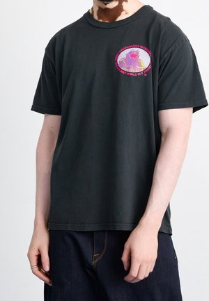 Maglietta nera in cotone a maniche corte con stampa grafica multicolore sul petto. Testo che circonda un disegno di un globo.