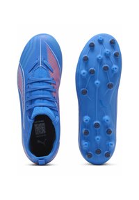 Niebieskie korki piłkarskie z teksturowanym wierzchem, kontrastującymi czerwonymi akcentami i podeszwą ze wzmocnieniem dla lepszej przyczepności. Zawierają wydrukowany kod QR wewnątrz.