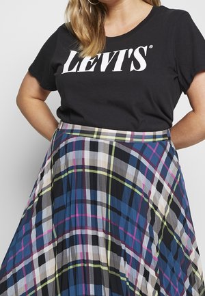 T-shirt noir à manches courtes Levi's avec logo blanc associé à une jupe plissée à carreaux multicolores présentant des motifs bleus, verts, roses et blancs.
