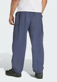 Pantalones cargo azul marino hechos de tela ligera, con múltiples bolsillos laterales y un ajuste holgado. Combinados con zapatos negros resistentes.