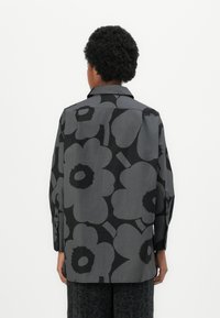 Svart og grå blomsterprydd skjorte med krage, lange ermer og knappede mansjetter. Stoffet har en jevn tekstur og en avslappet passform.