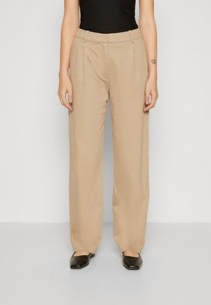 Beige wide-leg trousers made from a smooth, lightweight fabric. Features a flat front and two front pockets, paired with black flat shoes.