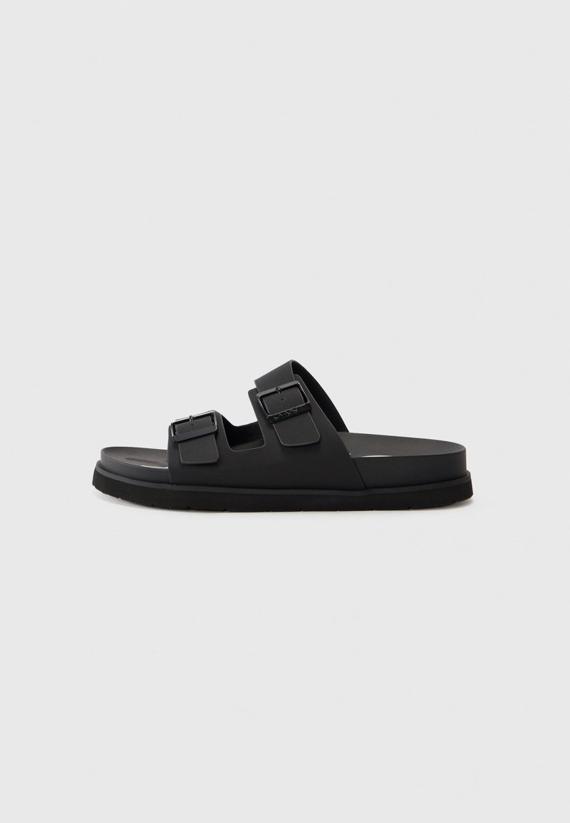Black rubber slide sandal with two adjustable straps, a textured footbed, and a flat sole. Minimalist design with clean lines.
