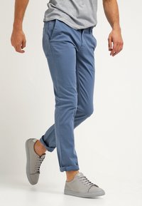 Chinos i ljusblå bomull, slim fit med sidofickor. Avslutade med uppvikta muddar, tillsammans med grå sneakers med snören.