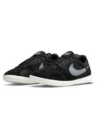 Black athletic shoes with suede and mesh material, featuring a grey accent swoosh, textured surface, and white rubber sole.