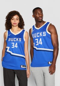 M�ėlyni NBA marškiniai su baltais ir juodais akcentais, ant kurių užrašyta "BUCKS" ir numeris "34". Pagaminti iš tinklinės medžiagos, su v-kaklo dizainu ir Nike logotipu.