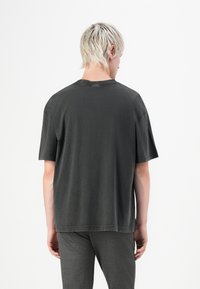 Dark gray cotton t-shirt with a relaxed fit, short sleeves, and a round neckline. Seam detailing is visible along the edges.