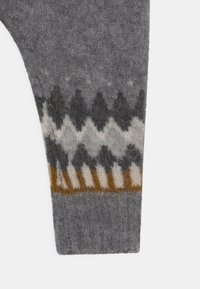 Šedá pletená ponožka s vyvýšeným vzorem v tmavě šedé, světle šedé a krémové barvě, doplněná hořčicově žlutým pruhem na lemu.