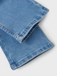 Tejido de mezclilla azul claro con una textura suave, que presenta puños doblados y costuras en contraste a lo largo de los bordes.
