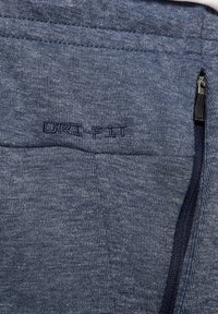 Navyblaue Dri-Fit Jogginghosen mit einem glatten, strukturierten Stoff, einer Reißverschlusstasche und dezenten Nähdetails am Bund.