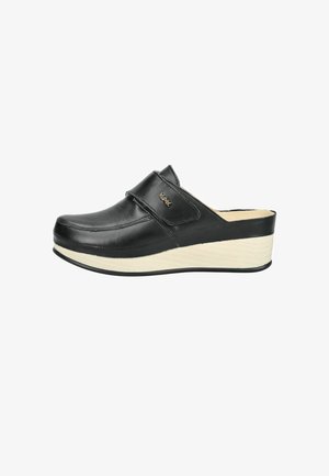 Scarpa in pelle nera senza lacci con suola platform beige e cinturino in velcro sulla parte superiore, vista laterale su sfondo bianco.