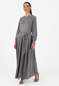 Gray long-sleeve dress with a round neckline, cinched waist, and pleated skirt; made from smooth fabric; finished with a tied belt.