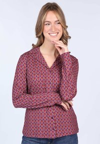 Long-sleeve shirt in a vibrant purple pattern with wave-like designs. Soft fabric, collared neckline, and buttoned front. Casual fit.