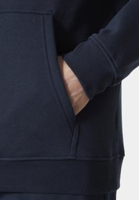 Donkerblauwe hoodie met een kangaroo pocket, geribbelde manchetten en een textuurstof, met een aansluitend ontwerp en schone stikdetails.