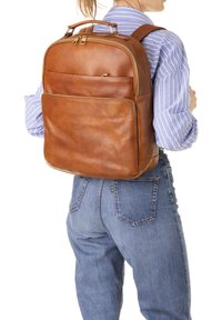 Zaino in pelle marrone con una finitura texturizzata, scomparti con zip e spallacci imbottiti. Presenta una tasca frontale e maniglie resistenti.