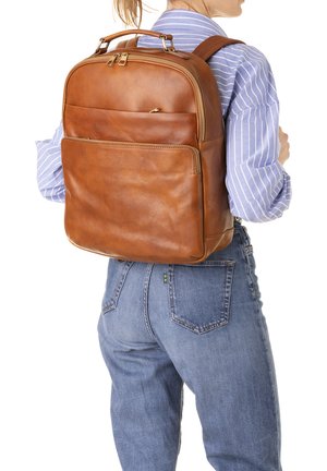 Sac à dos en cuir marron avec une finition texturée, compartiments zippés et bretelles rembourrées. Il dispose d'une poche avant et de poignées solides.