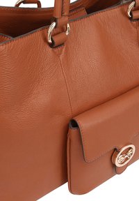 Bruine leren handtas met een gestructureerde afwerking, voorzien van gouden hardware en een voorvak met een ronde sluiting.