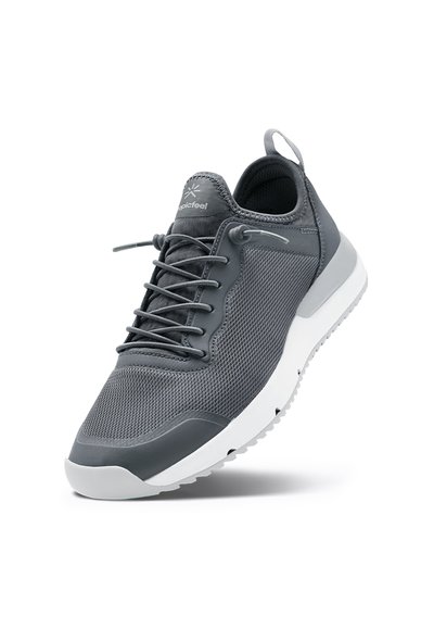 Grå sportskor med ovandel i mesh, rund tå och vit gummisula. Har elastiska snörningar och ett dragband vid hälen för enkel påtagning.