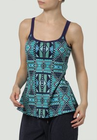 Top multicolore presenta motivi geometrici in teal, navy e bianco con scollatura a giro e orlo a peplum. Realizzato in tessuto leggero.
