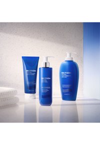 Tre Biotherm hudpleieprodukter: et blått rør, en pumpeflaske og en stor blå beholder, alle med stilige design og hvite etiketter.