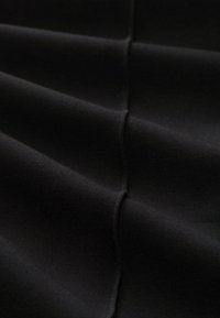 Schwarzer Stoff mit einer glatten Textur, der weiche Falten und Nähte aufweist. Das Material erscheint leicht und dehnbar, geeignet für verschiedene Anwendungen.