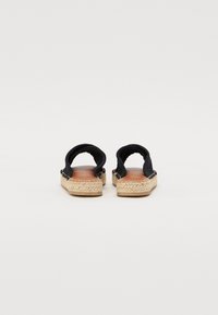 Svarte kanvas espadriller med naturlig jutesåle, åpen design bak og synlige sømmer langs kantene, med en glatt innside.