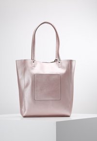 Metallisk rosa tote-väska med två långa handtag, rektangulär form, slät textur och en framträdande fyrkantig lapp på framsidan.