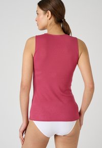 Canotta senza maniche, aderente, di un colore rosa intenso, con una texture a costine, scollatura rotonda e orlo che si ferma in vita.