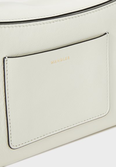 Cream leather handbag with gold "WANDLER" logo, featuring a smooth texture, stitched edge, and a flat pocket on the front.