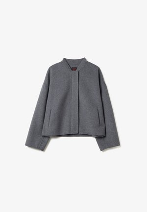 Veste en laine grise avec un col rond, des épaules tombantes et sans fermeture. Équipée de poches latérales et d'une silhouette ample. Texture douce.
