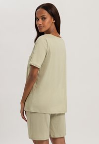 Conjunto de loungewear en verde claro que incluye una camiseta de manga corta con cuello redondo y un bolsillo, acompañado de pantalones cortos hasta la rodilla.