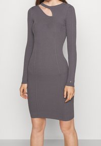 Robe à manches longues côtelée en gris doux avec un col rond et une découpe en forme de goutte. Silhouette ajustée avec un ourlet à hauteur du genou.