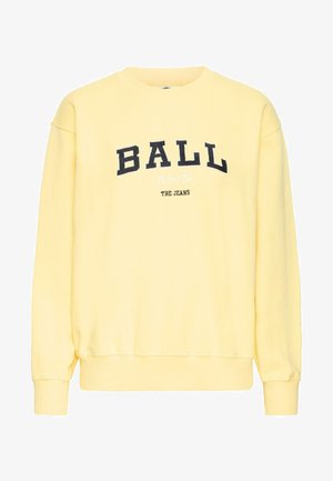 Geltona palaidinė su sutrauktu apykakle, ilgomis rankovėmis ir elastingais rankogaliais. Priekyje užrašyta "BALL" didelėmis tamsiomis raidėmis, o žemiau – "THE JEANS".
