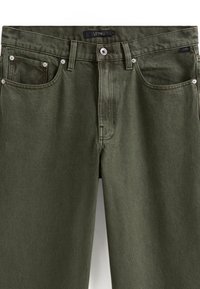 Zielone oliwkowe dżinsy o klasycznym kroju, z pięcioma kieszeniami, srebrnym okuciem i gładką fakturą. W widocznym miejscu na talii znajduje się metka marki.