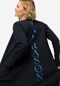Granatowy, oversize'owy sweatshirt z długim tyłem, z niebieskim napisem "LAURASON" na prawej stronie. Miękka tkanina z kieszeniami po bokach.