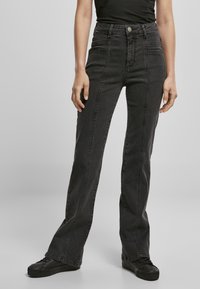 Jeans negros de cintura alta con corte recto, que presentan costuras en contraste, bolsillos frontales y un acabado elegante.