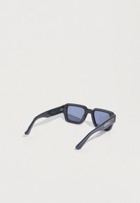 Sluneční brýle s tmavě modrým plastovým rámem, obdélníkového tvaru a čočkami s fialovým nádechem. Rukojeti jsou zdobeny strukturálními detaily.