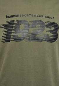 Olivengroene t-shirt met een zwart bedrukt grafisch ontwerp met de nummers "1923" en de tekst "sportswear since" in een strakke, moderne lettertype.