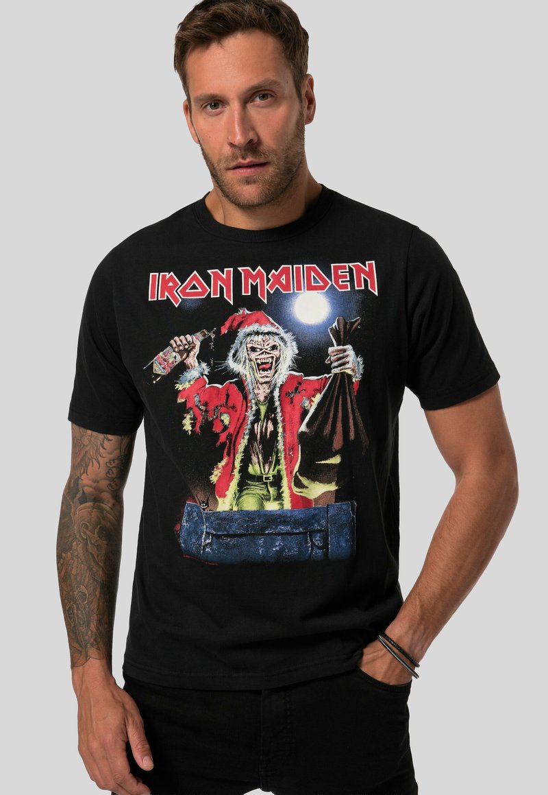 Černé bavlněné tričko s barevným grafickým motivem monstra v červeném kabátu, které drží tašku a láhev, s nápisem "IRON MAIDEN" nahoře.