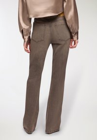 Brązowe dzwony z gładkiej tkaniny, z dwiema tylnymi kieszeniami i wysokim stanem, stylizowane z satynowym topem crop.