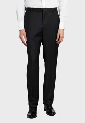 Pantaloni neri su misura realizzati in tessuto liscio, con un design a gamba dritta e tasche anteriori, abbinati a scarpe eleganti nere lucide.