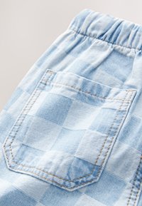 Pantaloncini in denim blu chiaro con motivo a scacchi, vita elasticizzata e tasca posteriore con dettaglio di cuciture visibili.
