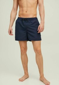 Sötétkék fürdőshorts, rugalmas derékkal és zsinórral, oldalsó zsebekkel és könnyű, sima anyagból készült.