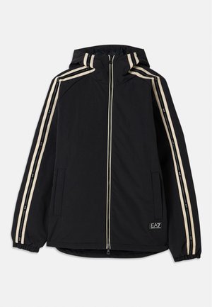 Black hooded jacket with two vertical cream stripes along the sleeves, front zipper, side pockets, and a logo patch on the lower front.