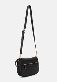 Sac à bandoulière en cuir noir avec une forme courbée, poche zippée à l'avant et sangle réglable. Il présente un matériel en doré et une finition texturée.