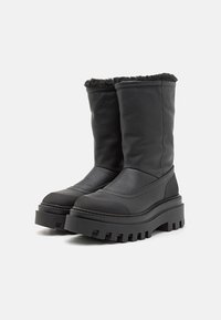 Botas de cuero negro hasta el tobillo con un acabado texturizado, suela de goma gruesa y ribete de piel sintética en la parte superior. Diseño de plataforma elevada.
