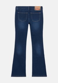 Jeans acampanados de color azul oscuro con una textura suave, que cuentan con dos bolsillos traseros y una etiqueta de marca marrón en la cintura.