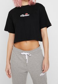 Svart kortärmad t-shirt med "ellesse"-logotyp i vitt och rött. Matchad med grå sweatpants med vit dragsko och logotyp.