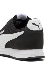 Scarpa da ginnastica bianca e nera con tomaia in tessuto strutturato, dettagli in pelle liscia, suola in gomma e logo PUMA sul tallone e sul lato.